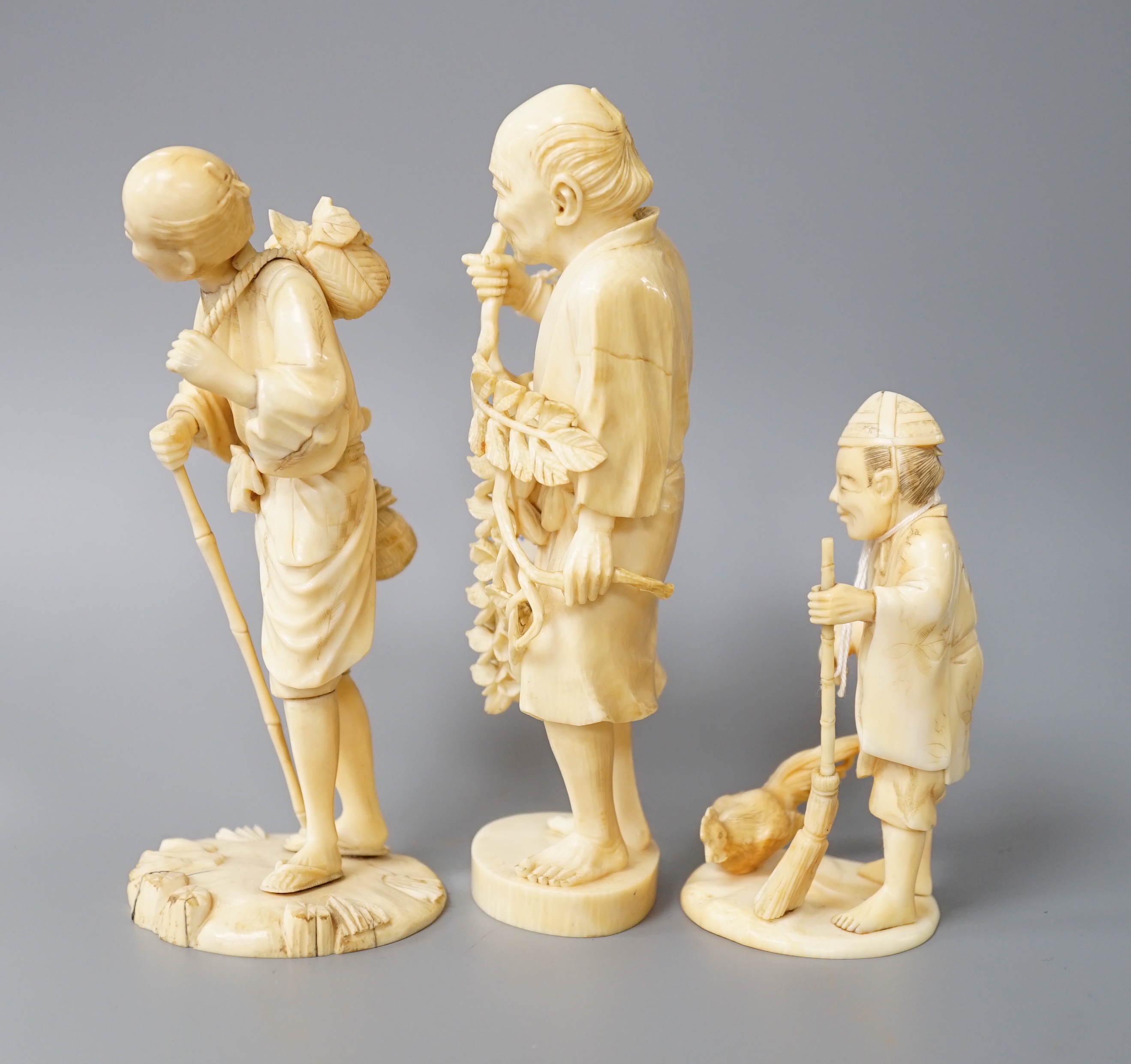A 19th century Japanese ivory okimono of a gentleman holding a branch, another sectional figure of a gentleman with a walking stick, both signed and another 20th century okimono. Tallest 15.5cm